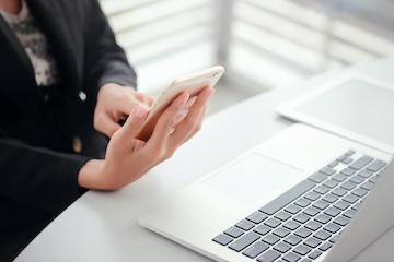 Person holding Mobile device over a laptop